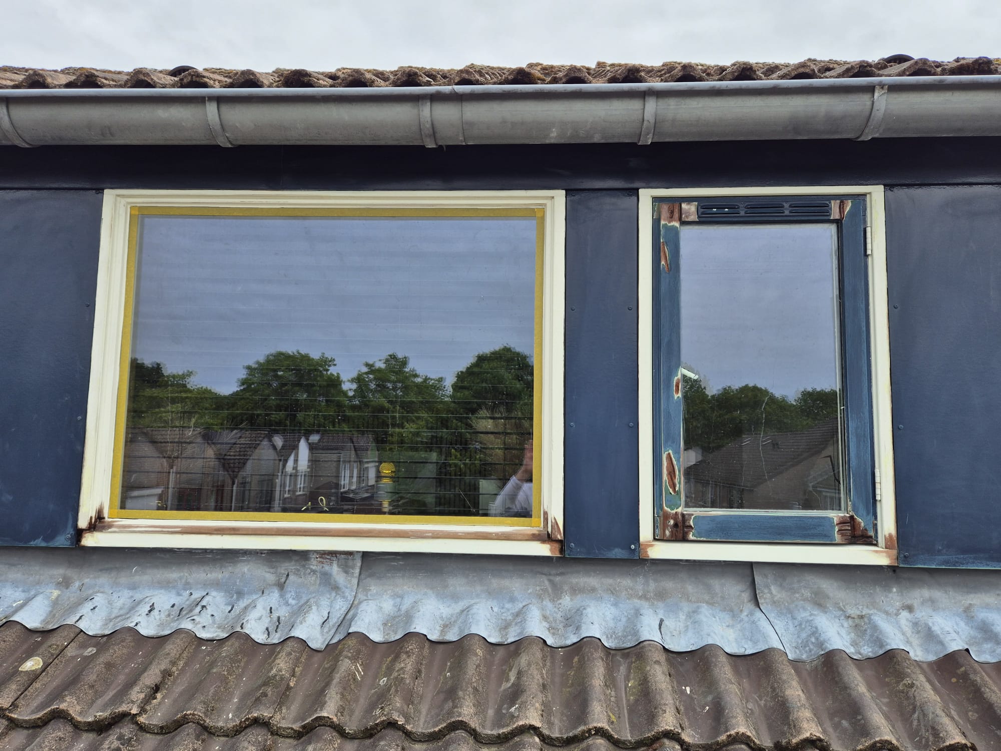 Dakkapel met afgebladderde lak en houtrot voor de renovatie