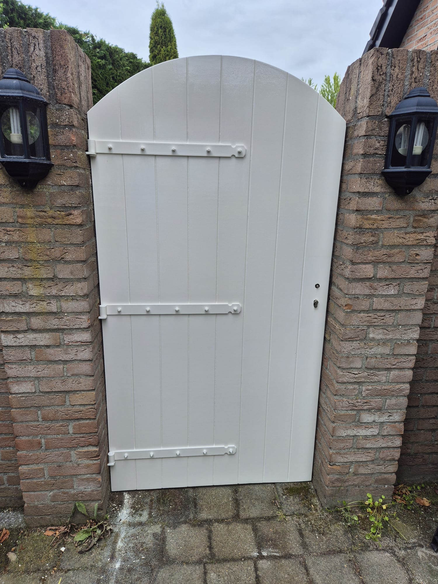 Gemonteerde witte tuinpoort tussen gemetselde kolommen